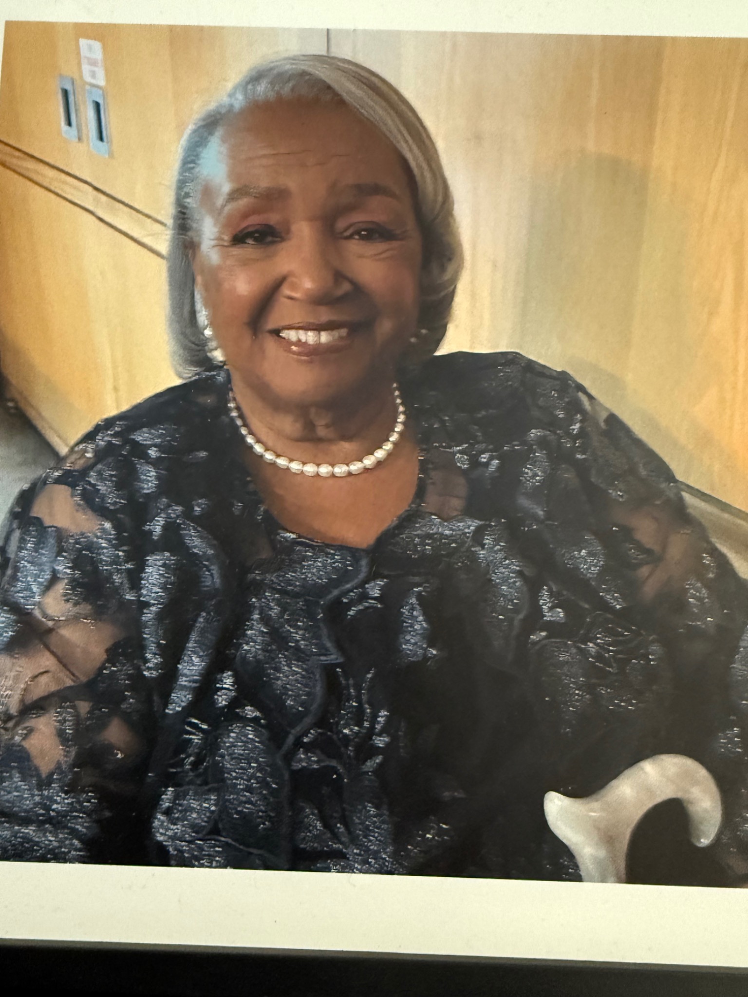Joyce Banks smiling in her floral dress and pearl necklace
